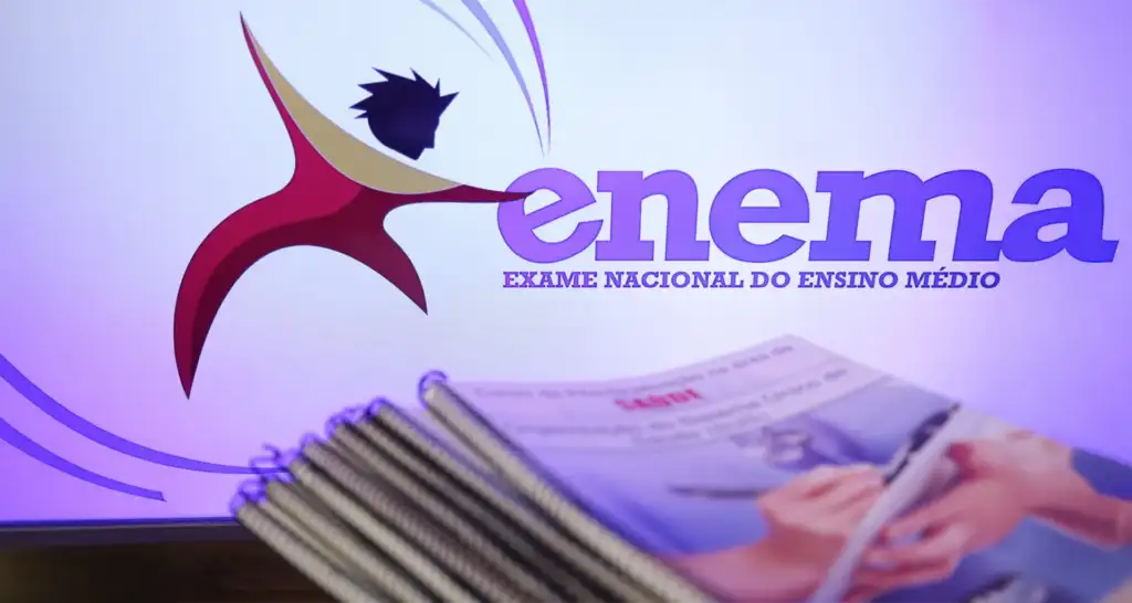 Logotipo do ENEM (Exame Nacional do Ensino Médio) ao fundo com cadernos espiralados de estudo em primeiro plano.